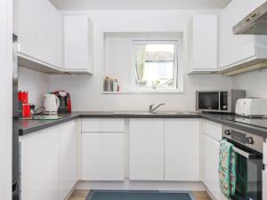 a white kitchen with white cabinets and a window at Brixham Breeze Cabin in Brixham +13 photos