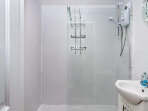 a white bathroom with a shower and a sink at Brixham Breeze Cabin in Brixham