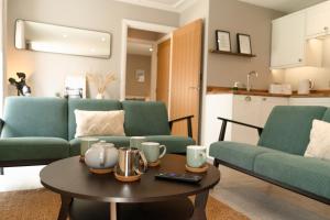 a living room with two green couches and a table at Fieldside Cottage in Scarborough