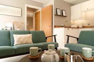 a living room with two green couches and a table at Fieldside Cottage in Scarborough