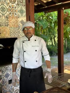 a man in a chefs uniform standing next to a grill at Costa do Sauipe Casa dentro do complexo hoteleiro in Costa do Sauipe +173 photos