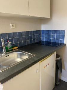 a kitchen counter with a sink and blue tiles at Studio rénové gare Dijon in Dijon
