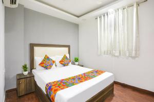 a white bedroom with a large bed with colorful pillows at Comfy Stay Hotels 2nd Floor in New Delhi
