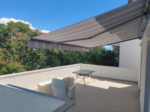 a patio with a table and chairs under awning at RIBARIĆ in Banjol