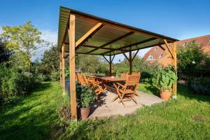 - un pavillon en bois avec une table et des chaises dans la cour dans l'établissement Ferienwohnung Wittensee, à Bünsdorf