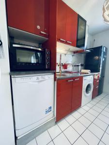 a kitchen with red cabinets and a white dishwasher at 15 min walk to DisneylandParis, 5 min walk to Val d'Europe Mall and train RER A, Monyhome apartment for 4 persons in Chessy