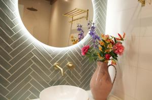 un jarrón con flores en la encimera del baño con espejo en De Bosuil, en Bergen 7 fotos más
