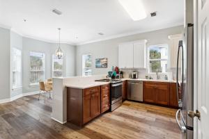 a kitchen with white cabinets and wooden floors and windows at Rockaway Beach in Santa Rosa Beach