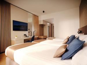 a hotel room with three beds and a desk at Hotel Riviera - Terme & Wellness LifeClass in Portorož