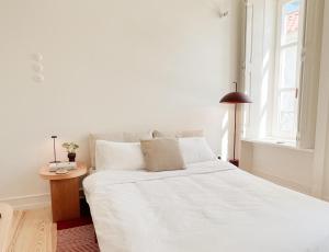 a white bed in a room with a window at Maison Boheme - Cascais Historic Apartment in Cascais
