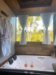 eine Badewanne in einem Zimmer mit zwei Weingläsern in der Unterkunft Chalés do Figa in Visconde De Maua