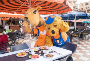 プラヤ・デ・ラス・アメリカスにあるCoral Compostela Beachの2体のマスコットが食べ物が置かれたテーブルの横に立っている