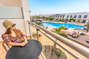 a woman sitting on a balcony looking out at a pool at Coral Cotillo Beach in El Cotillo