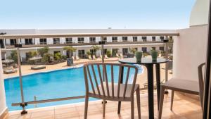 a balcony with a table and chairs and a pool at Coral Cotillo Beach in El Cotillo