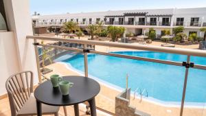 a balcony with a table and a swimming pool at Coral Cotillo Beach in El Cotillo