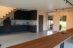 a kitchen with black cabinets and a wooden table at Sodyba Divaiva in Anykščiai
