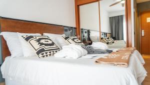 a bedroom with a large white bed with a large mirror at Coral Cotillo Beach in El Cotillo