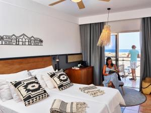 a woman sitting in a hotel room with a bed at Coral Cotillo Beach in El Cotillo