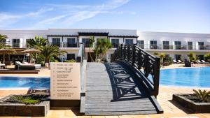 a wooden walkway leading to a resort with a swimming pool at Coral Cotillo Beach in El Cotillo