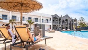 a group of people sitting in chairs by the pool at a resort at Coral Cotillo Beach in El Cotillo