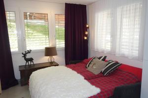 Schlafzimmer mit einem roten und weißen Bett und Fenstern in der Unterkunft Studio Collinetta in Zermatt