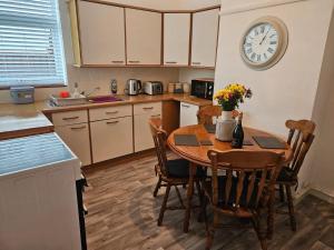 a kitchen with a table and a clock on the wall at Victoria Beach Cottage in Prestatyn