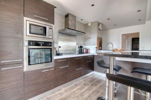 a kitchen with wooden cabinets and a microwave at L'Arène de coeur - appt avec piscine partagée in Toulouse +6 photos