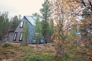 a house in the woods with a black roof at Trasti & Trine Boutique Hotel in Alta