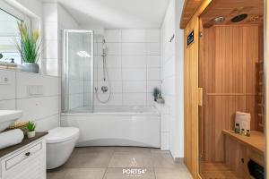 a white bathroom with a tub and a toilet at Ferienwohnung La Mer Olpenitz in Olpenitz