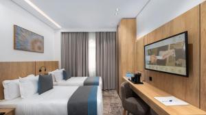 a hotel room with two beds and a flat screen tv at فندق السعفة الذهبية Assaafa Golden Hotel in Al Madinah