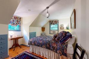 ein Schlafzimmer mit einem Bett und einem Schreibtisch und zwei Fenstern in der Unterkunft Dog Cove Cottage in Center Harbor