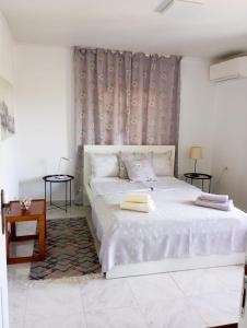 a white bed with two towels on it in a room at Villa Leah Apartment in Yerakiní