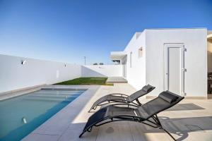 a pair of chairs sitting on a patio next to a swimming pool at Villa Kalma in Chiclana de la Frontera