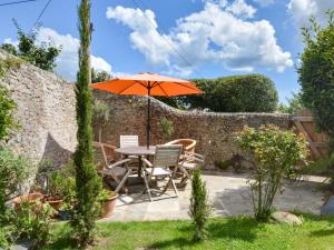 a table and chairs with an umbrella in a garden at 3 Bed in Charmouth 93420 in Charmouth