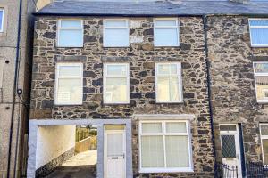 an old stone house with white doors and windows at Beautifully Presented 5 BR House with Hot Tub in Pwllheli