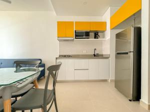 eine Küche mit Tisch und Stühlen und einem Kühlschrank in der Unterkunft Apartamento Salinas del Mar - balcon y vista al mar - By Bedviajes in Playa Bello Horizonte