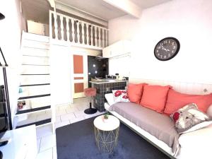a living room with a couch and a clock on the wall at le jardin de mae in Bouc-Bel-Air