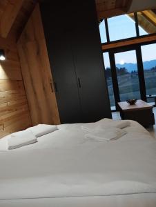 a white bed in a room with a large window at NORTH VILLAS Žabljak in Žabljak