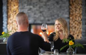 a man and a woman sitting at a table with a glass of wine at Wilderness Hotel Juutua in Inari