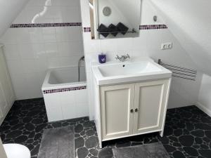 a white bathroom with a sink and a tub at Landhaus Tewel Hotel mit Restaurant 14KM vom Heide-Park in Tewel +17 photos