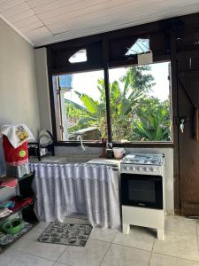 una cucina con un lavandino, un fornello e una finestra di Casa Privativa em Arraial d'Ajuda - 1 Quarto com 2 camas, Cozinha e Banheiro - 10 Minutos do Centro a Arraial d'Ajuda