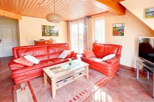 a living room with two red leather couches and a tv at Ferienwohung 3 Sandorn in Kölpinsee
