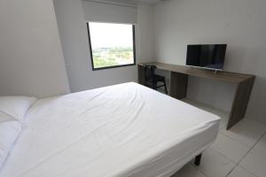 a bedroom with a bed and a desk and a television at Apartemen Riverdale Cikarang by Alfa Rooms in Rawasuren