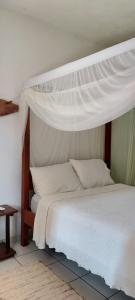 a bedroom with a white bed with a canopy at Pousada do Titi in Caraíva