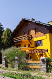 a yellow house with a fence in front of it at Las Rocas By Base 41 in San Carlos de Bariloche
