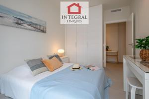 a white bedroom with a bed with a hat on it at Apartament Mar Blau in Palamós