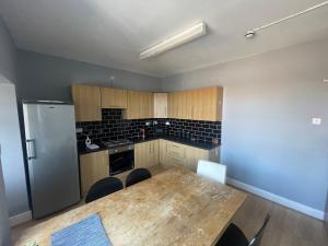 eine Küche mit Holztisch und Kühlschrank in der Unterkunft The Clifton Guest House in Liverpool