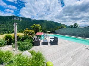 a pool with chairs and a table on a wooden deck at Villa des 3 fontaines in Annecy