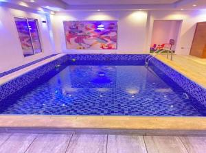 a swimming pool with blue tiles in a room at فندق كروان جده in As Salamah