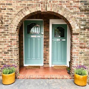 two green doors on a brick building with two plants at Flat1Hove- renovated, 2BR, patio, beach, free onsite parking in Hove